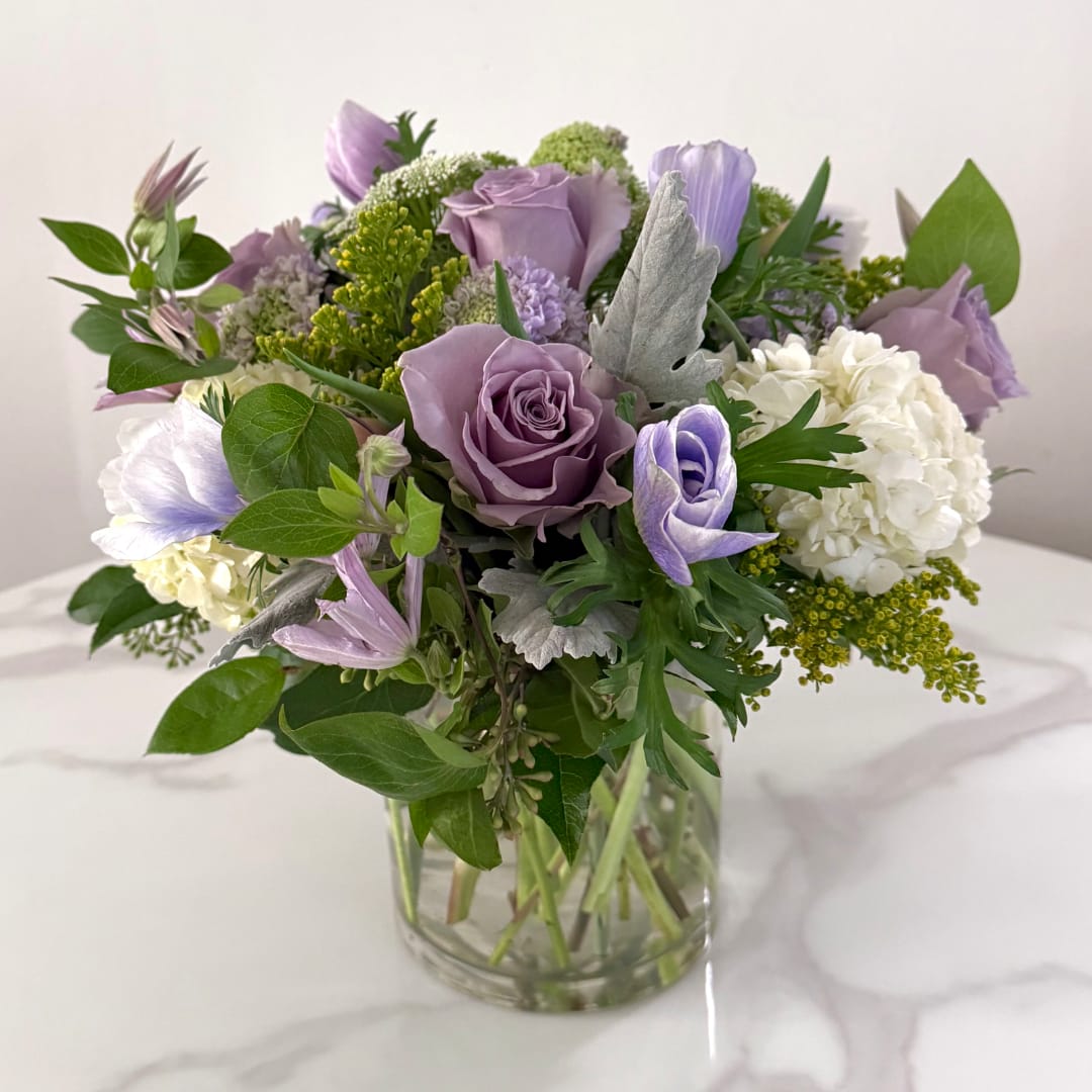 Lavender roses and white hydrangeas in a clear glass vase