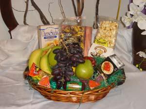 Gift basket with fruit, snacks, and candy in a wicker tray