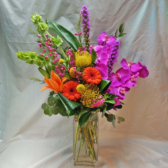 Bright mixed bouquet in a clear glass vase with orange, pink, and yellow blooms