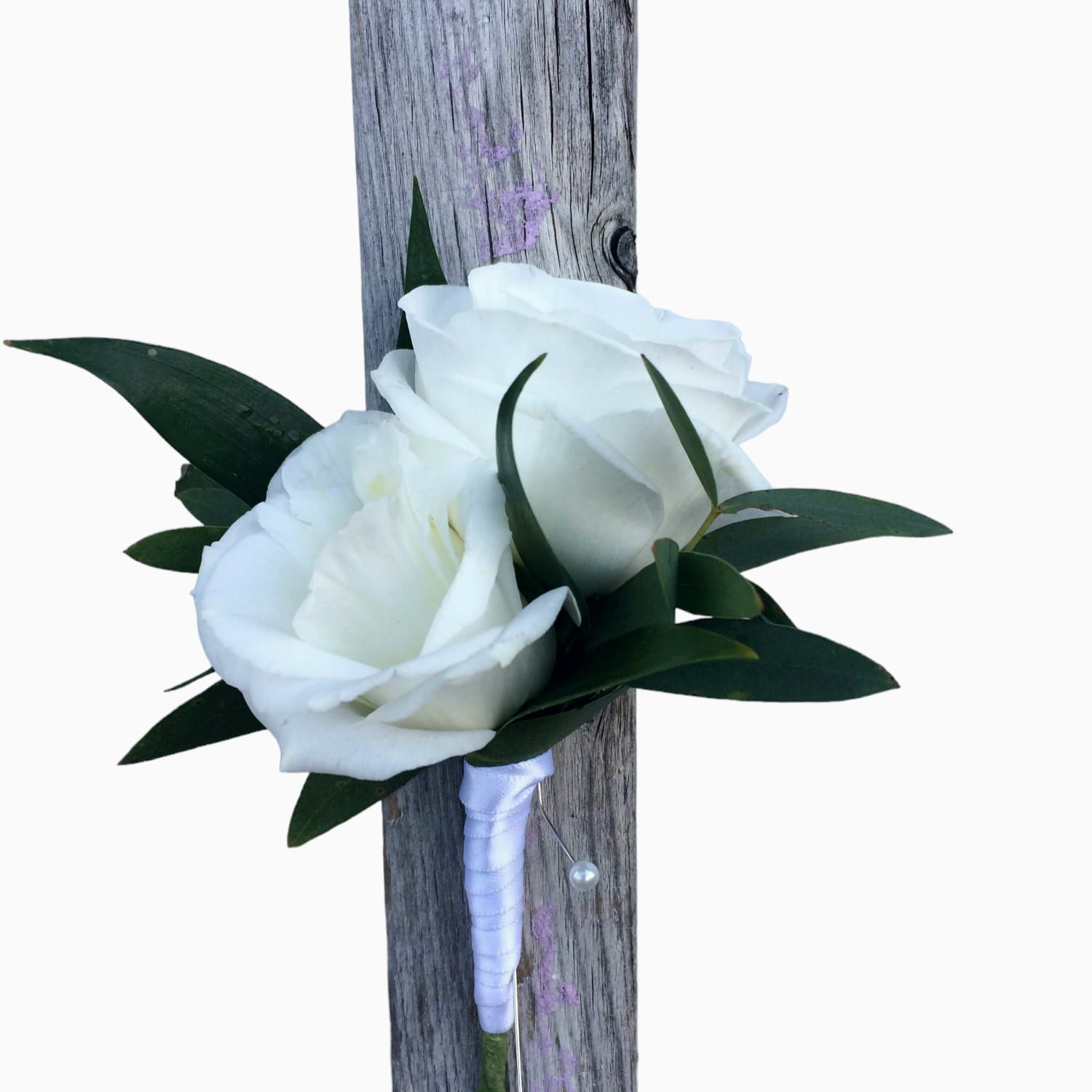 White rose boutonniere with dark green leaves on a wrapped stem