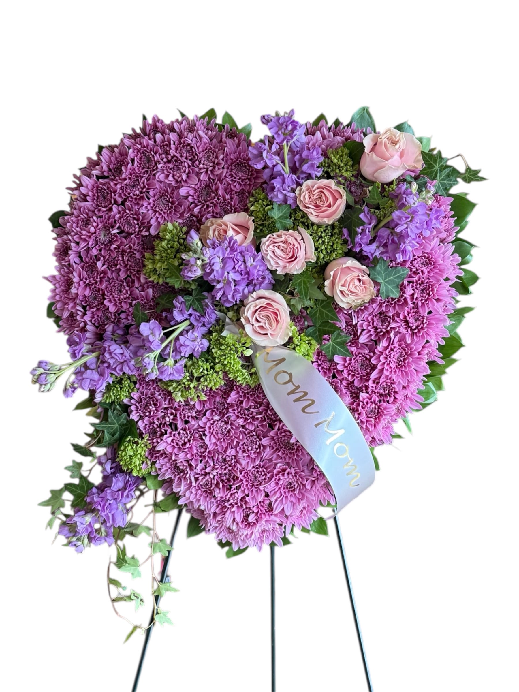 Graceful Heart Tribute - A beautiful heart-shaped standing floral arrangement that conveys love, remembrance and heartfelt sympathy. The combination of rich purple and soft pink creates a feeling of warmth and tenderness.  It includes a banner, the one pictured says "Mom Mom" but please tell us what you would like it to say. This is done on a solid 18" heart.