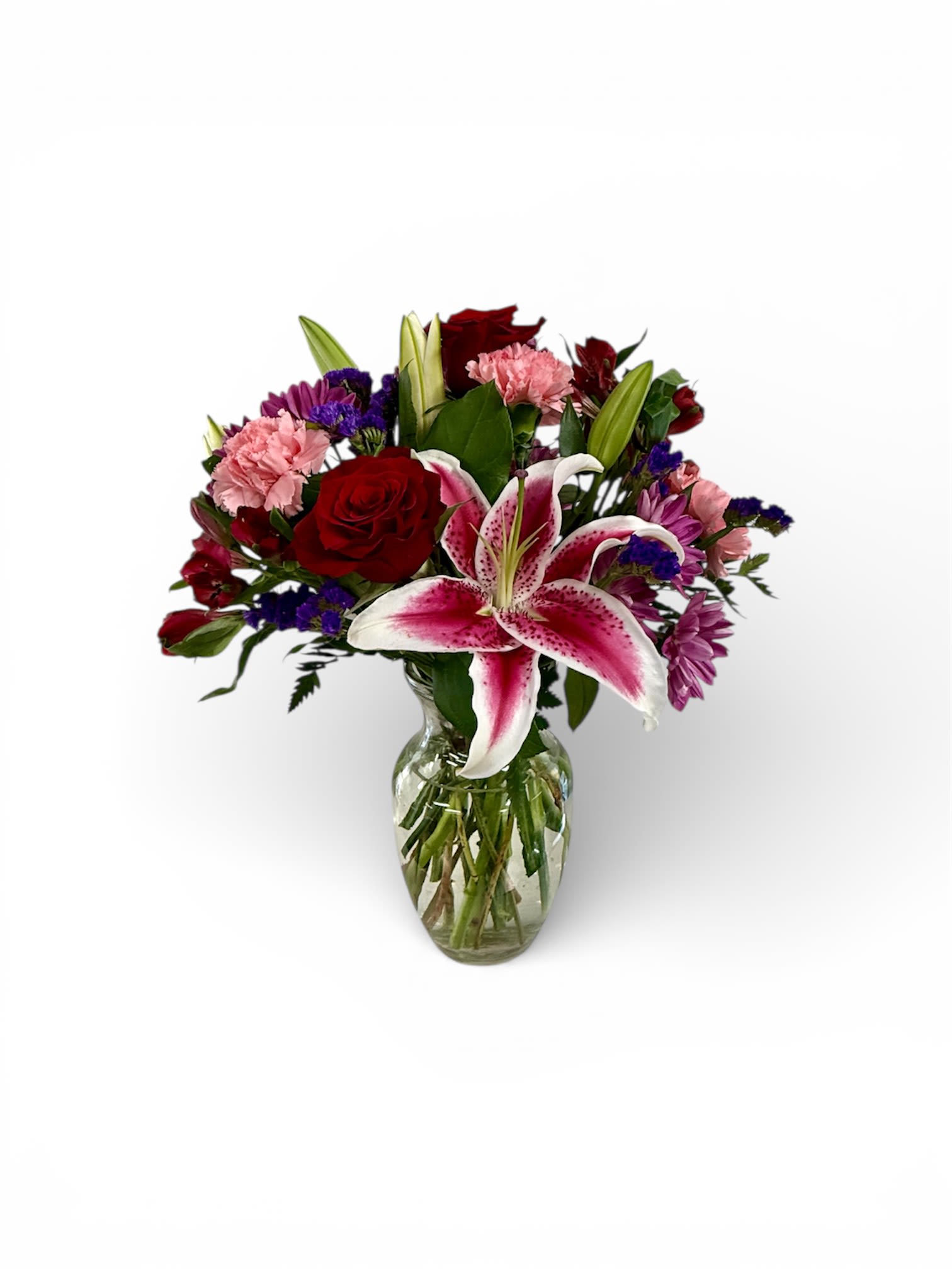 Bouquet of red roses, pink carnations, and a pink lily in a glass vase