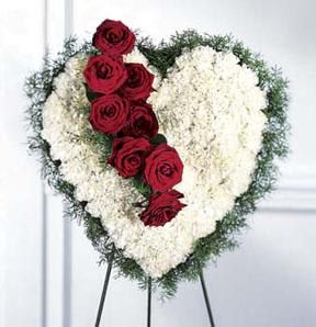 Heart-shaped floral spray with red roses and white flowers on a stand