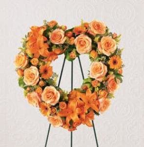 Orange rose and lily wreath on a black stand