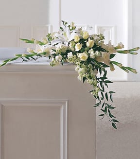 White floral casket spray with trailing greenery
