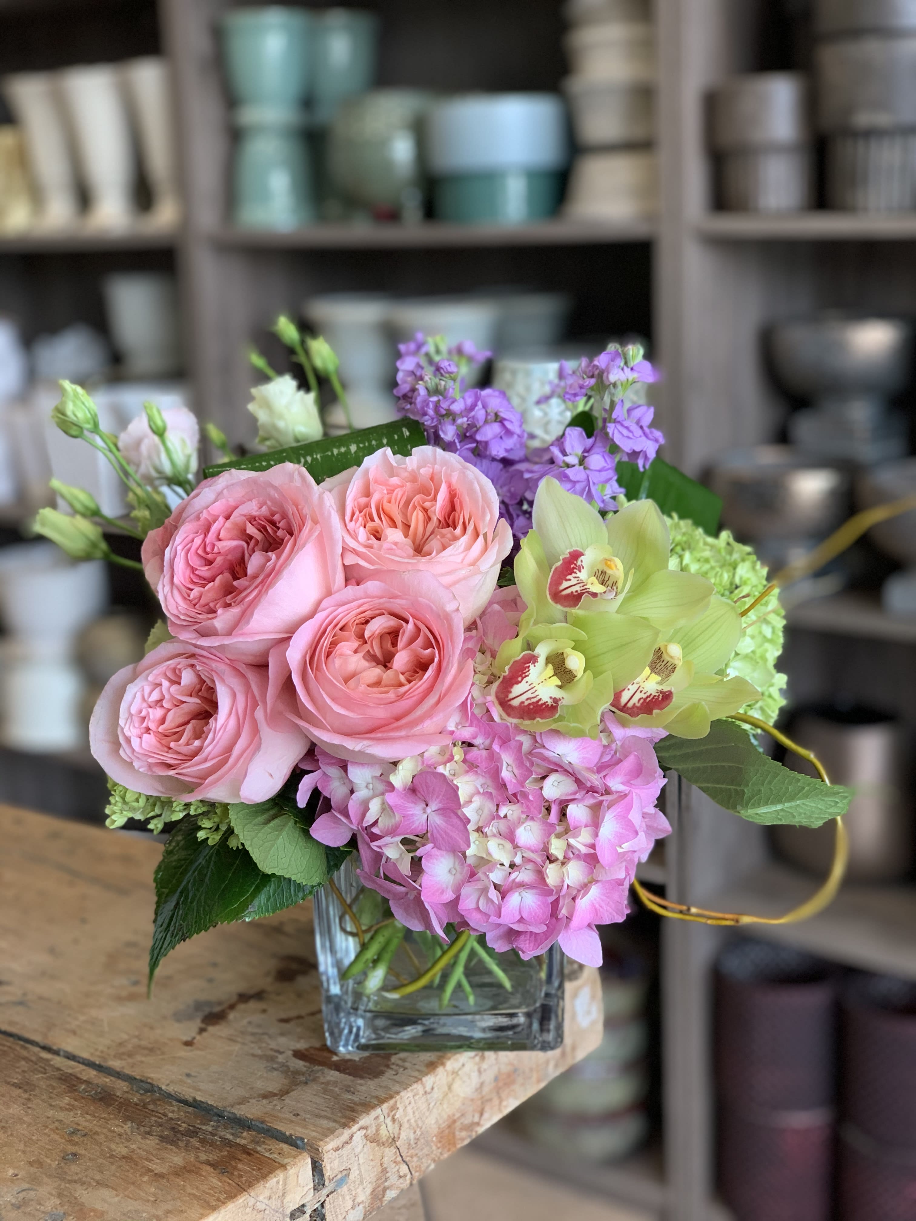 Sammy's Xpression  - A lush, compact design featuring a harmonious blend of pink and green hydrangeas, fragrant stock, elegant cymbidium orchids, and premium pink Expression garden roses. Known for their naturally full, open bloom and impressive longevity, these garden roses add a romantic, refined touch from the moment they arrive. This thoughtfully arranged piece radiates charm and sophistication—perfect for any space or occasion.