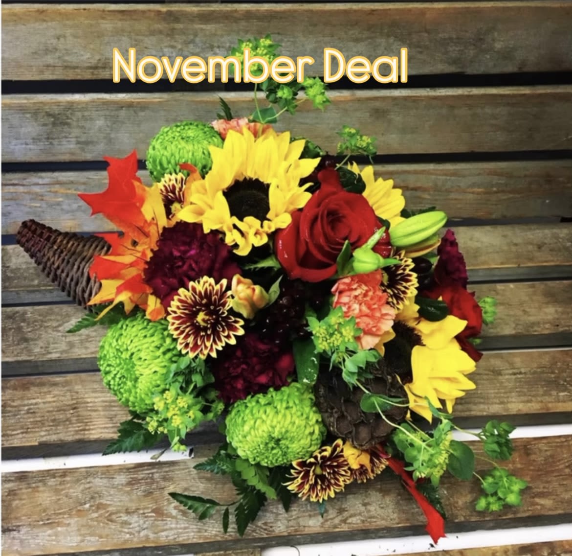 Mixed bouquet with sunflowers, red roses, and green mums on a rustic wood background