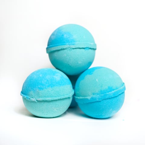 Three blue bath bombs stacked on a white background