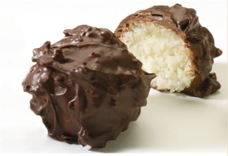 Two chocolate-covered coconut candies on a white surface