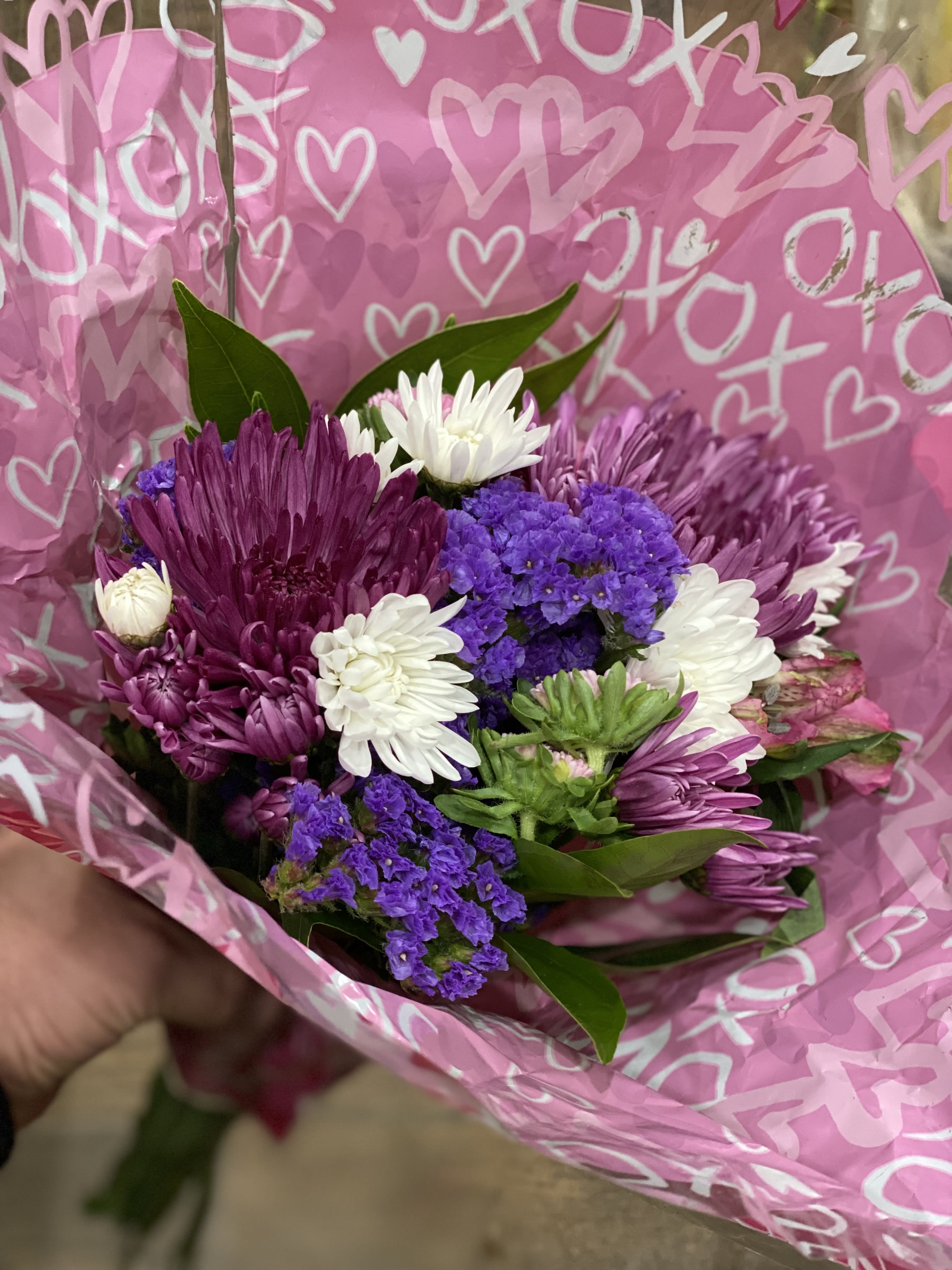 Bouquet of purple and white chrysanthemums wrapped in pink heart paper