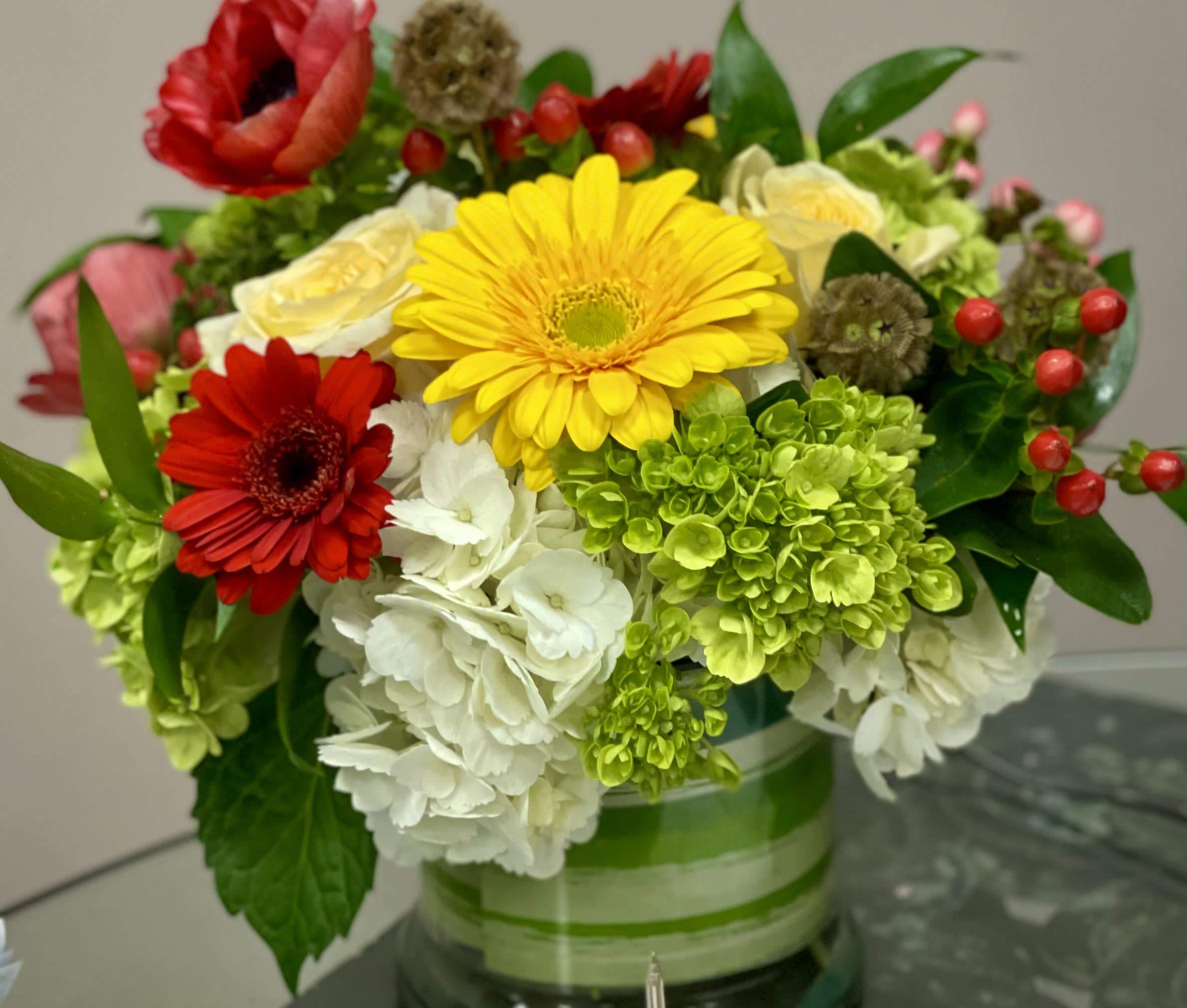 Mixed bouquet with gerbera daisies, hydrangeas, and roses in a glass vase