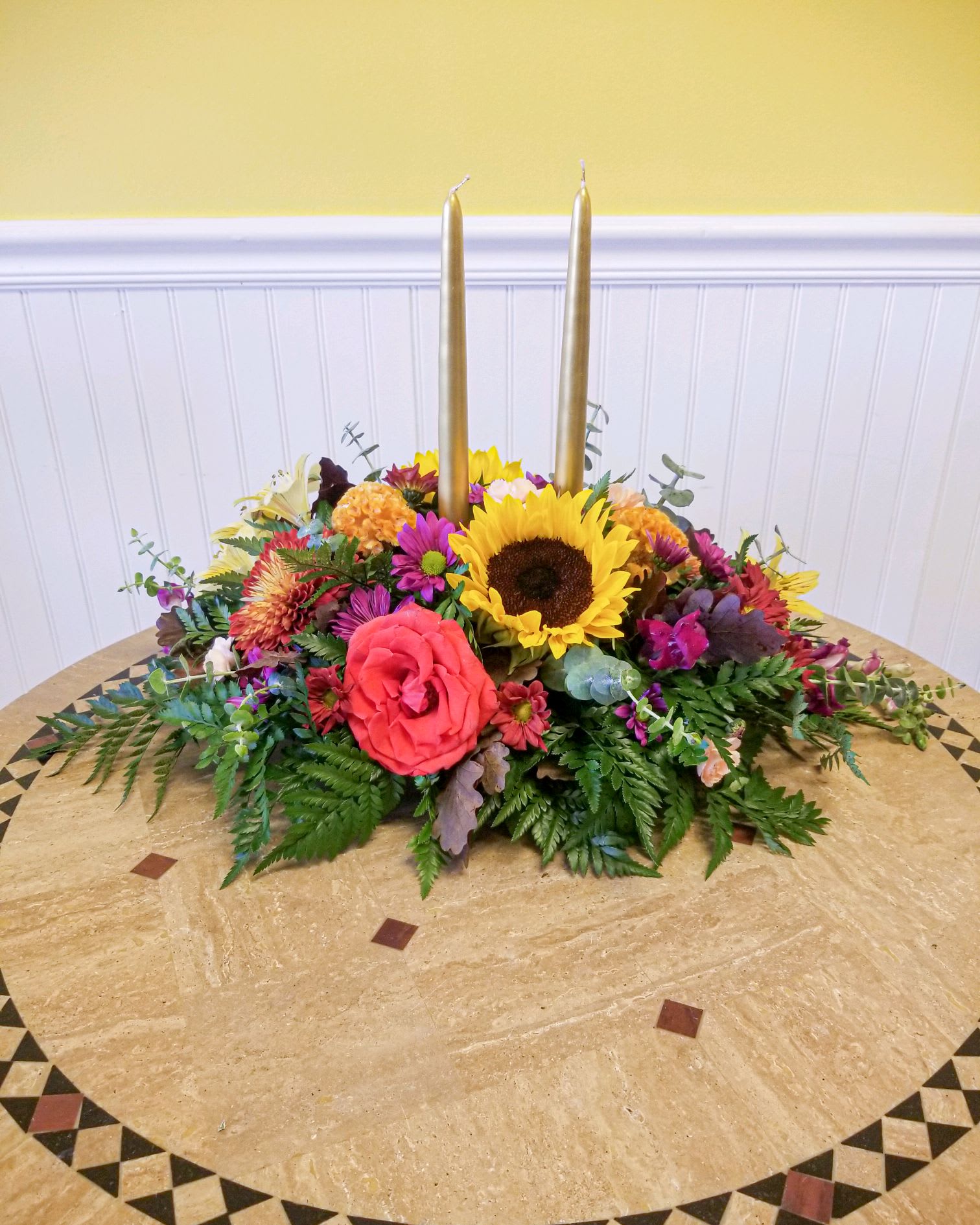 Colorful floral centerpiece with two tall gold candles