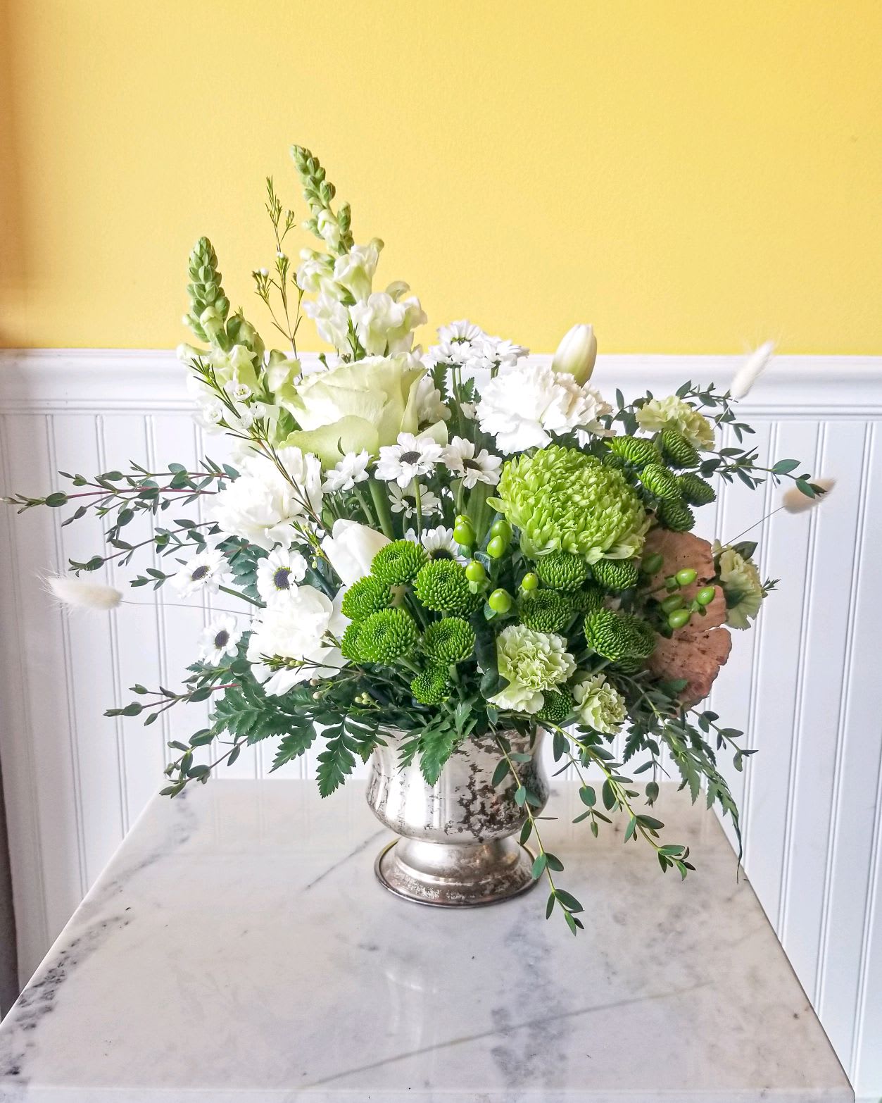 White and green mixed flower arrangement in a silver vase