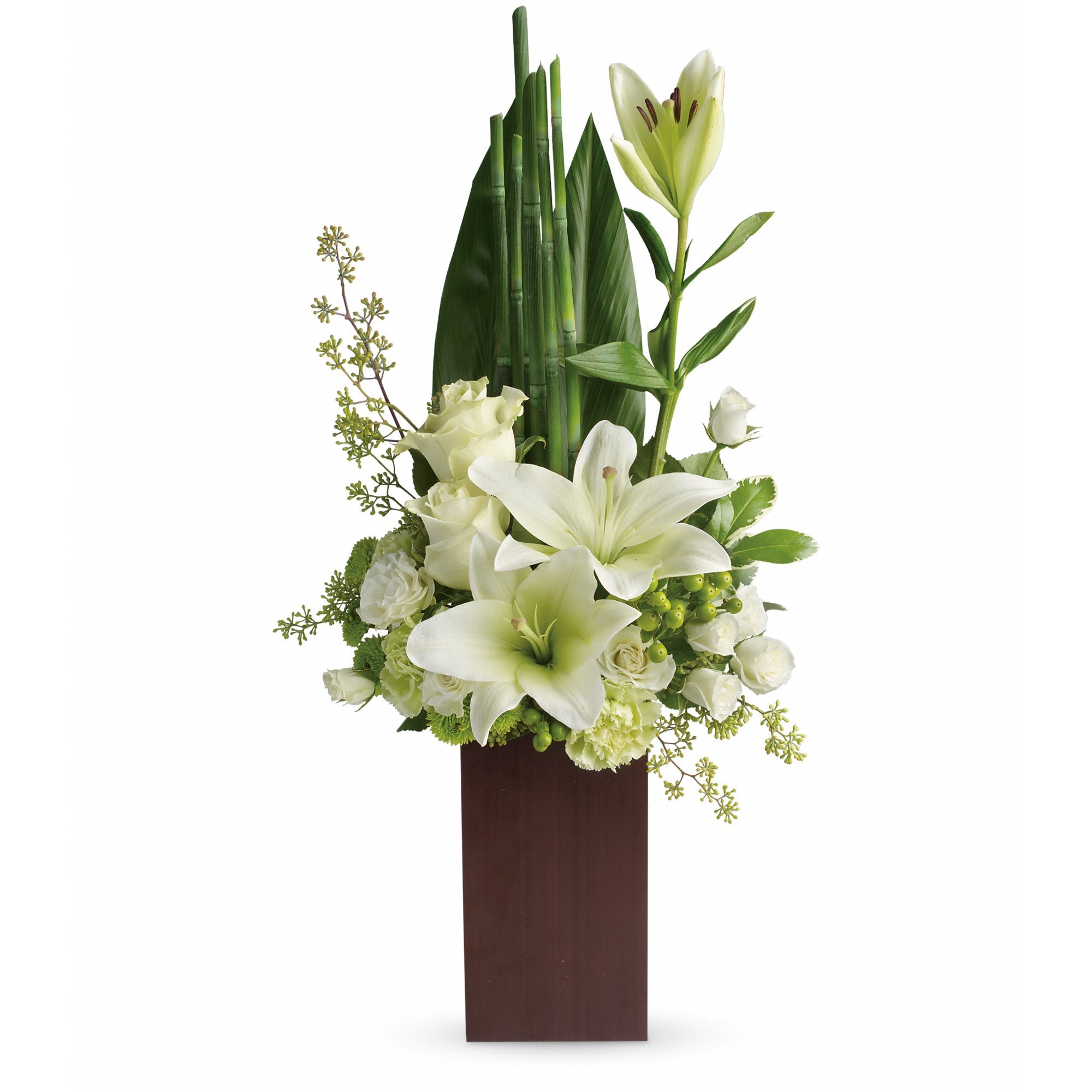 Tall modern arrangement of white lilies and roses in a dark rectangular vase with green accents