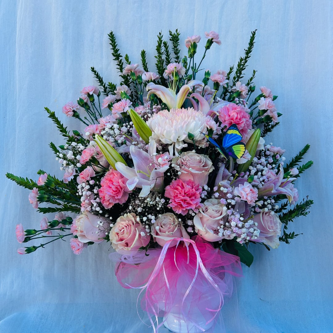 Pink and white mixed bouquet in a white vase with a pink ribbon