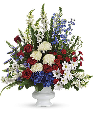 Mixed red, white, and blue floral arrangement in a white vase