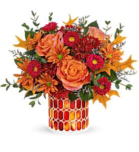 Orange and red floral arrangement in a patterned vase