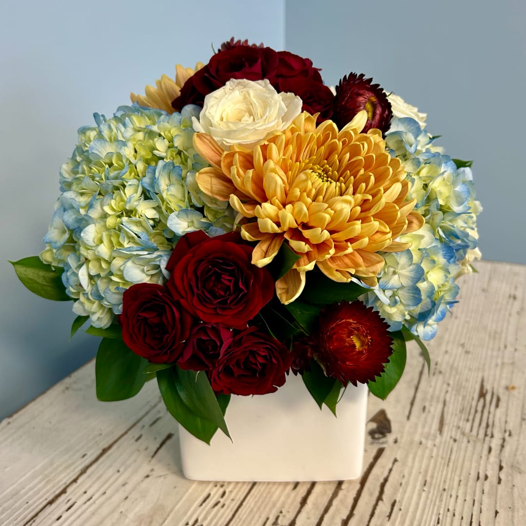 Bouquet of hydrangeas, roses, and chrysanthemums in a white vase