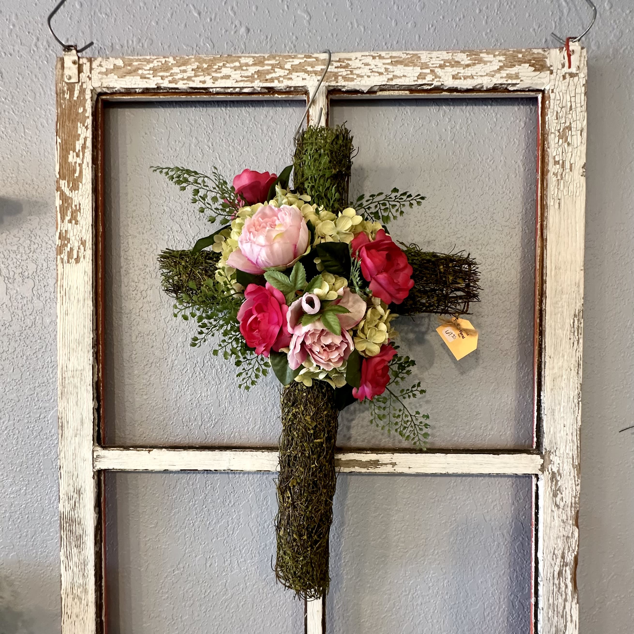Floral cross with pink and red flowers on a rustic wooden frame