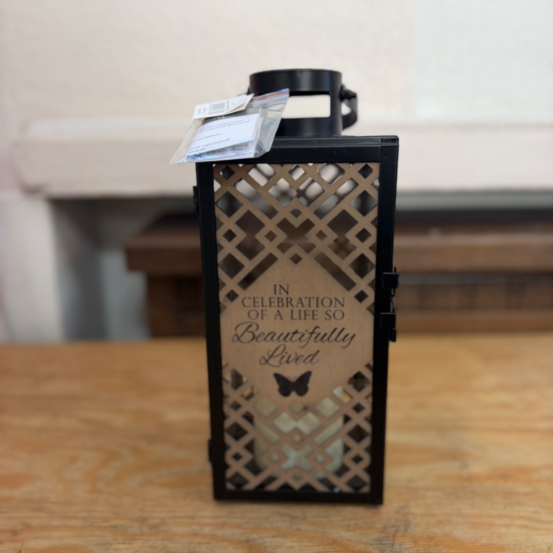 Decorative black lantern with a memorial message on a wooden table