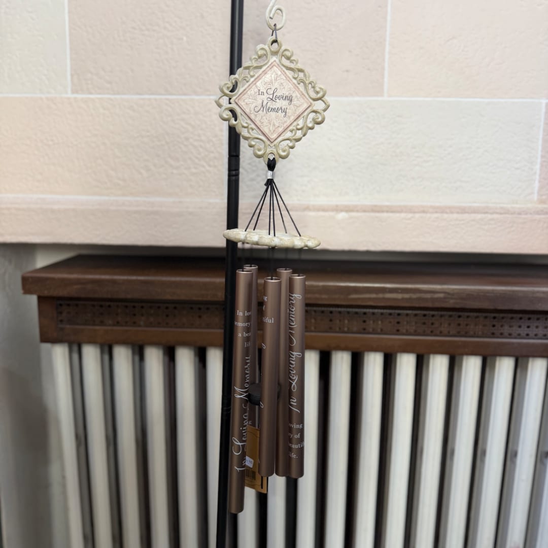 Memorial wind chime hanging indoors with an "In Loving Memory" plaque