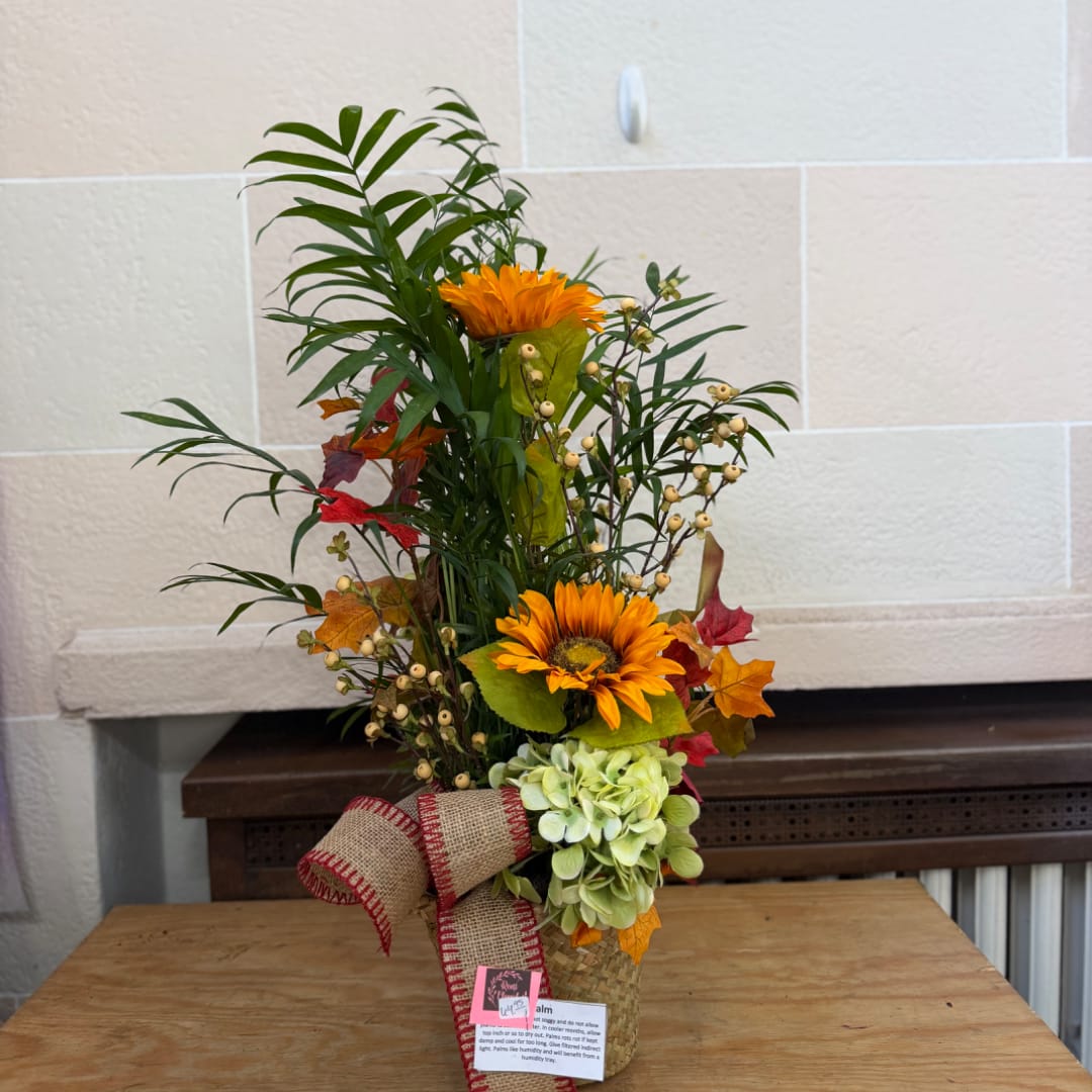 Tall autumn floral arrangement with orange blooms in a woven vase
