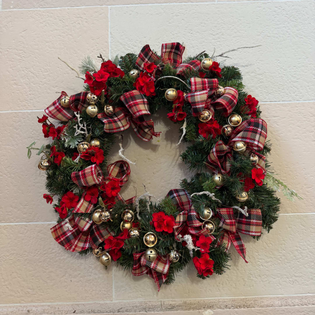 Christmas wreath with red flowers, plaid ribbon, and gold bells
