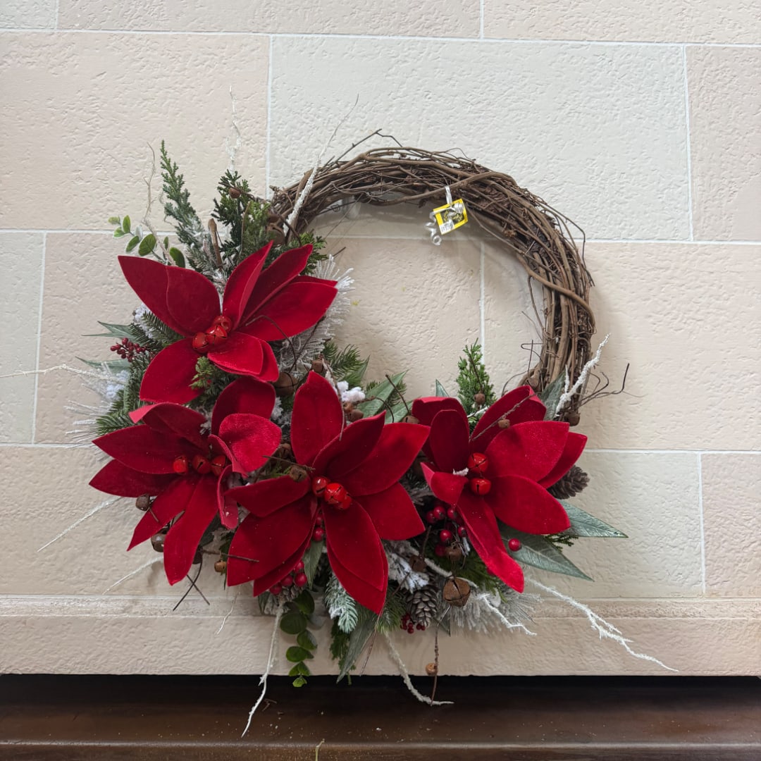 Red poinsettia wreath with evergreen accents on a wall
