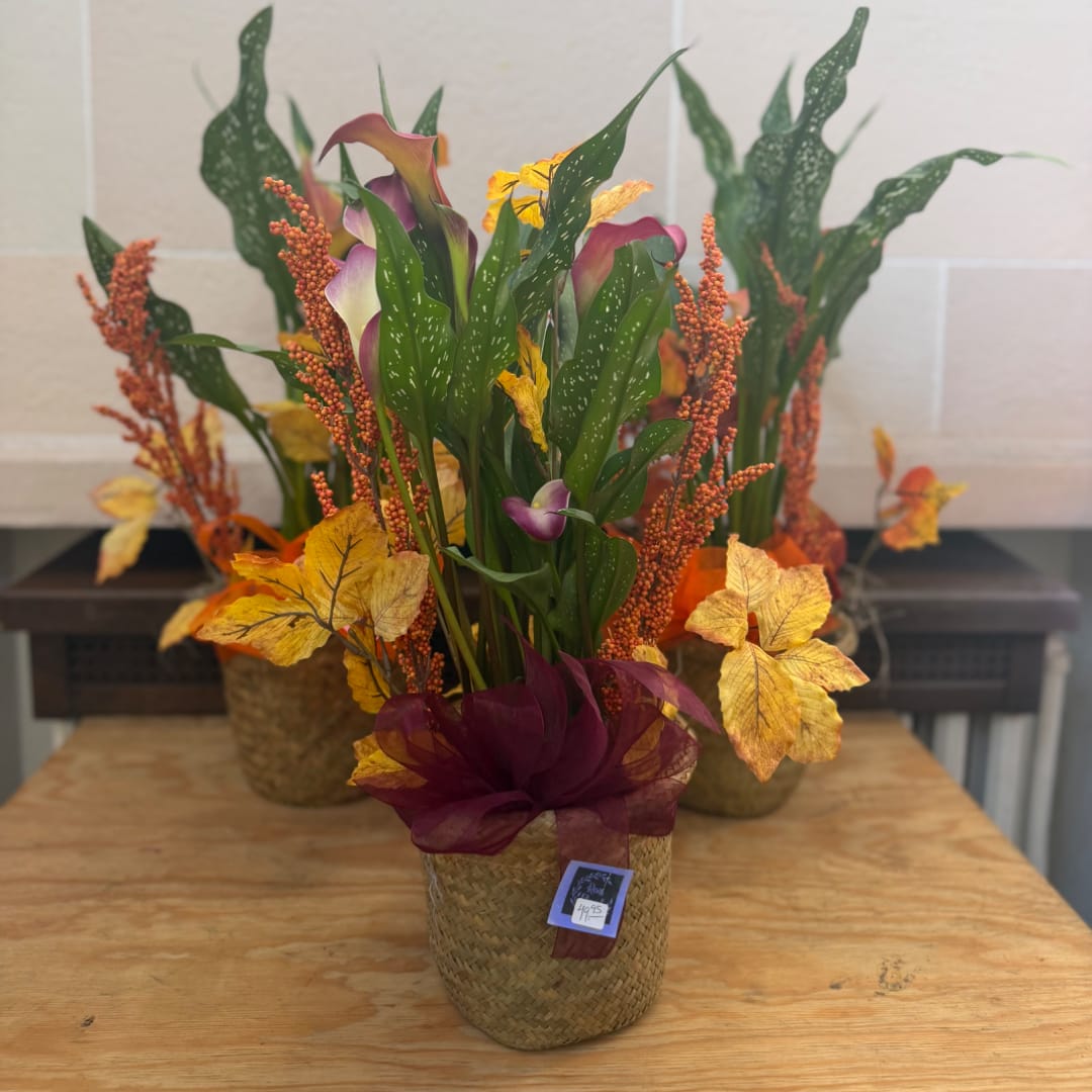 Autumn floral arrangement in a woven basket with purple calla lilies and yellow leaves