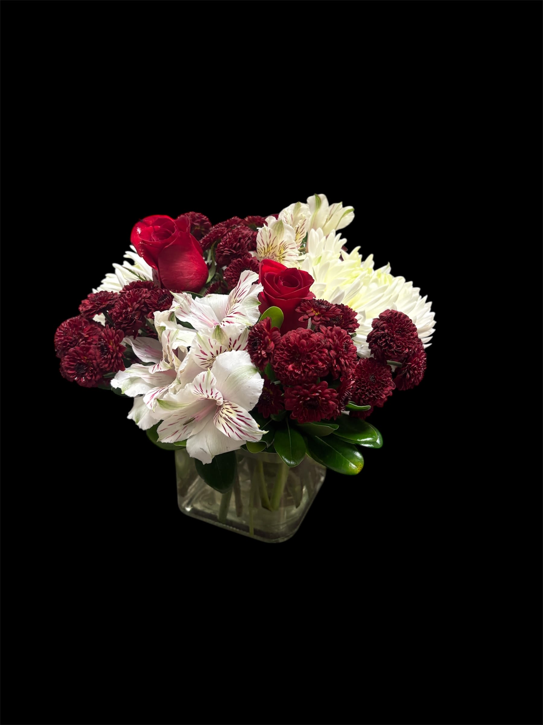 Red roses and white flowers arranged in a square glass vase