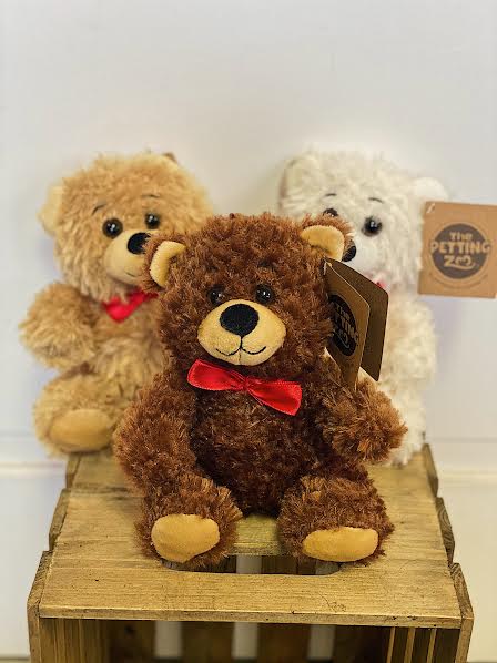 Three teddy bears with red bows on a wooden crate