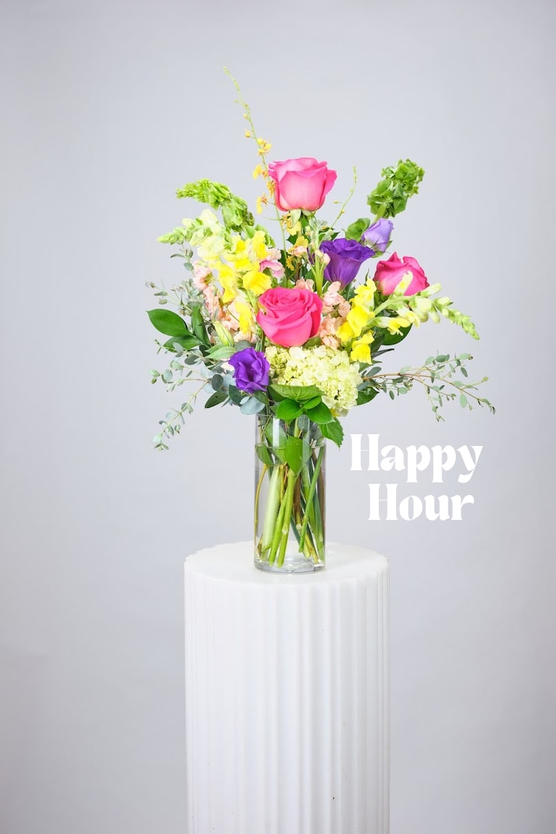 Mixed bouquet of pink, purple, and yellow flowers in a clear glass vase