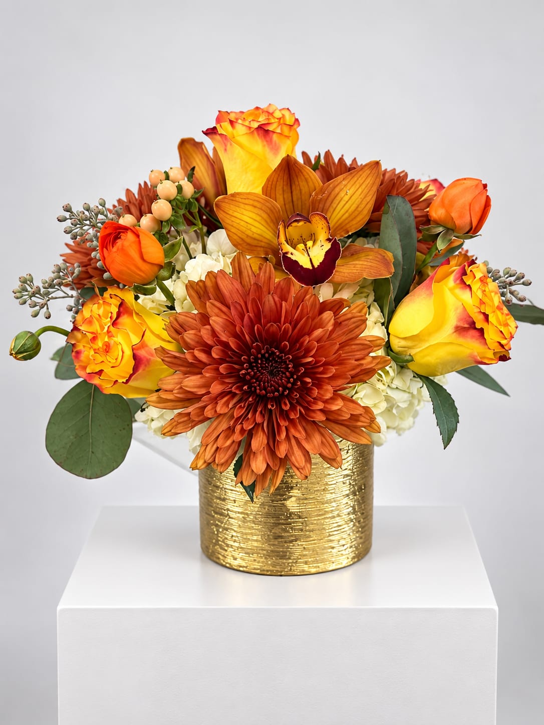 Orange and yellow floral arrangement in a gold vase