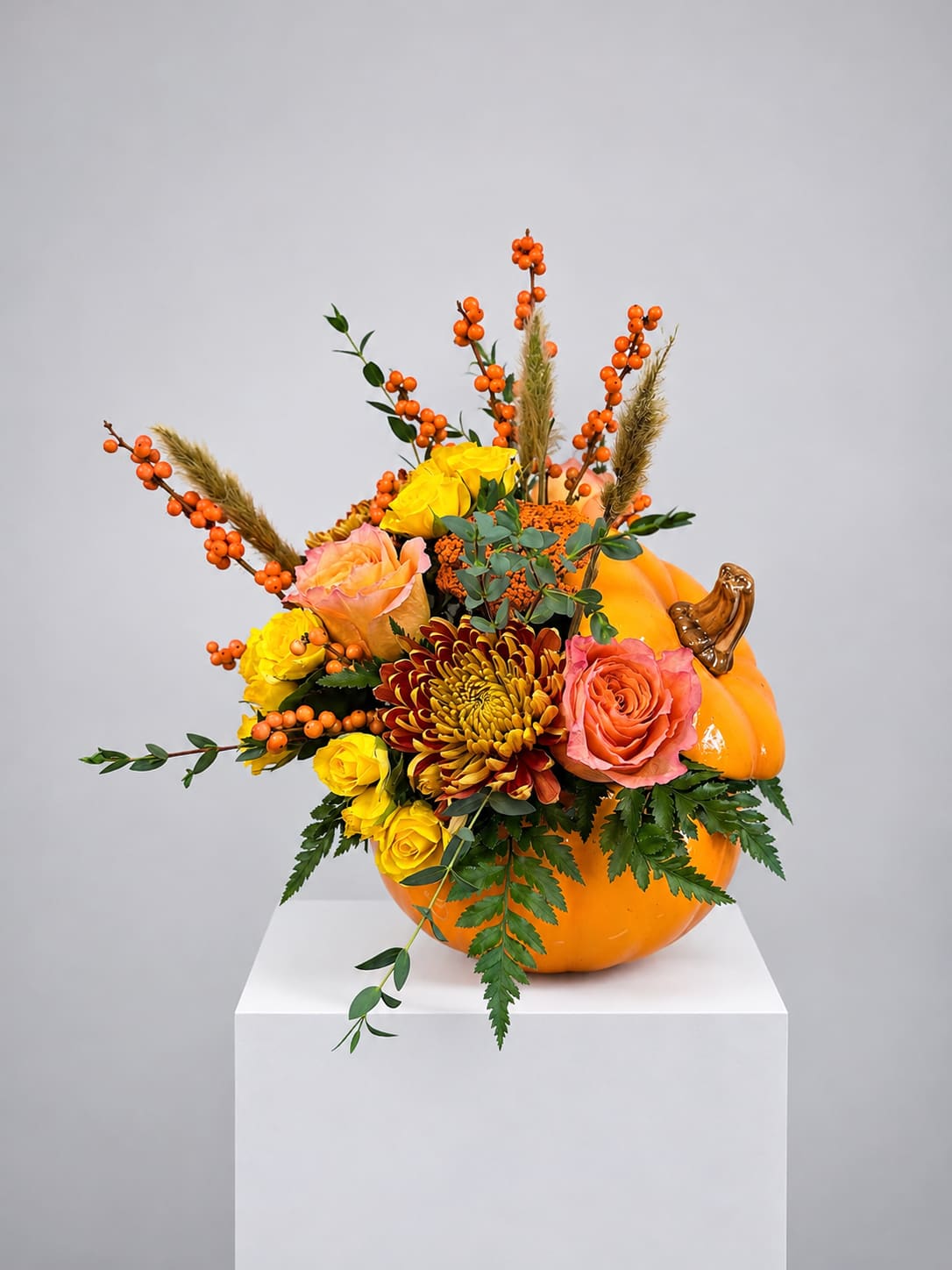 Pumpkin-shaped arrangement with roses, mums, and orange berries