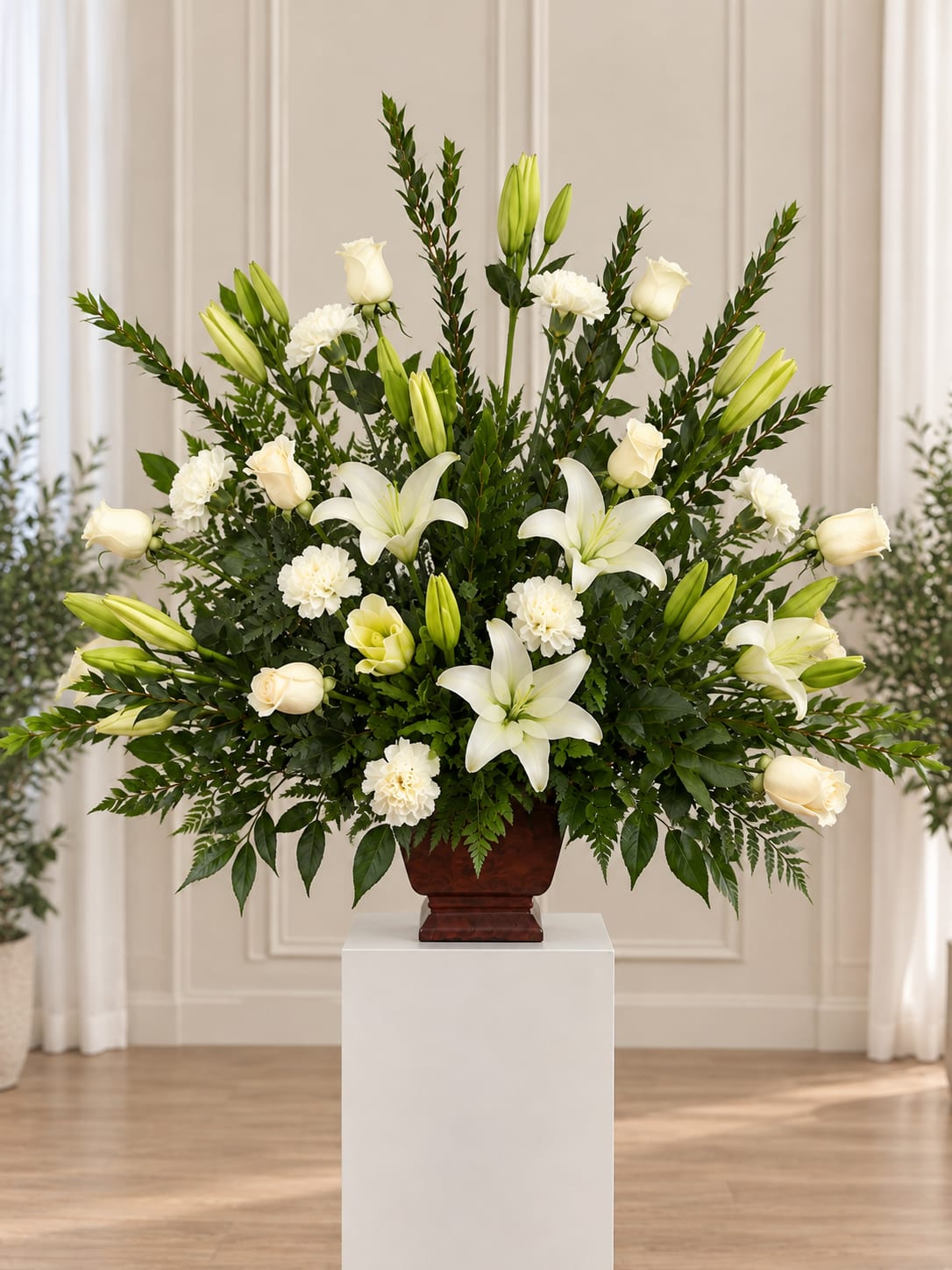 White lilies and roses arranged in a dark vase on a pedestal