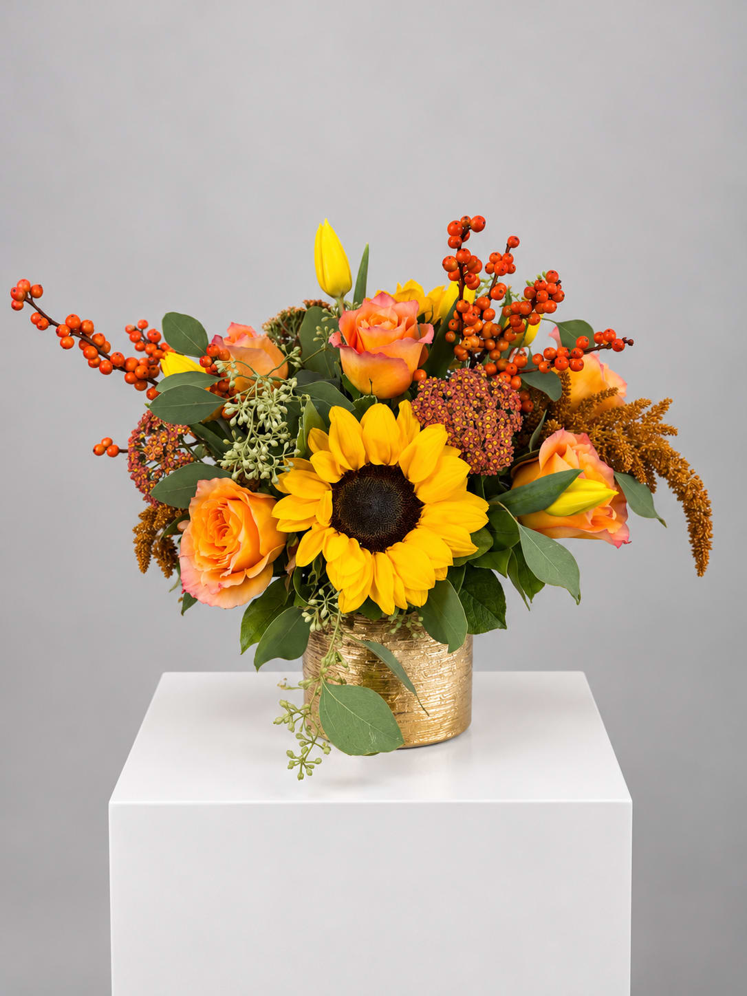 Sunflower and peach rose arrangement in a gold vase