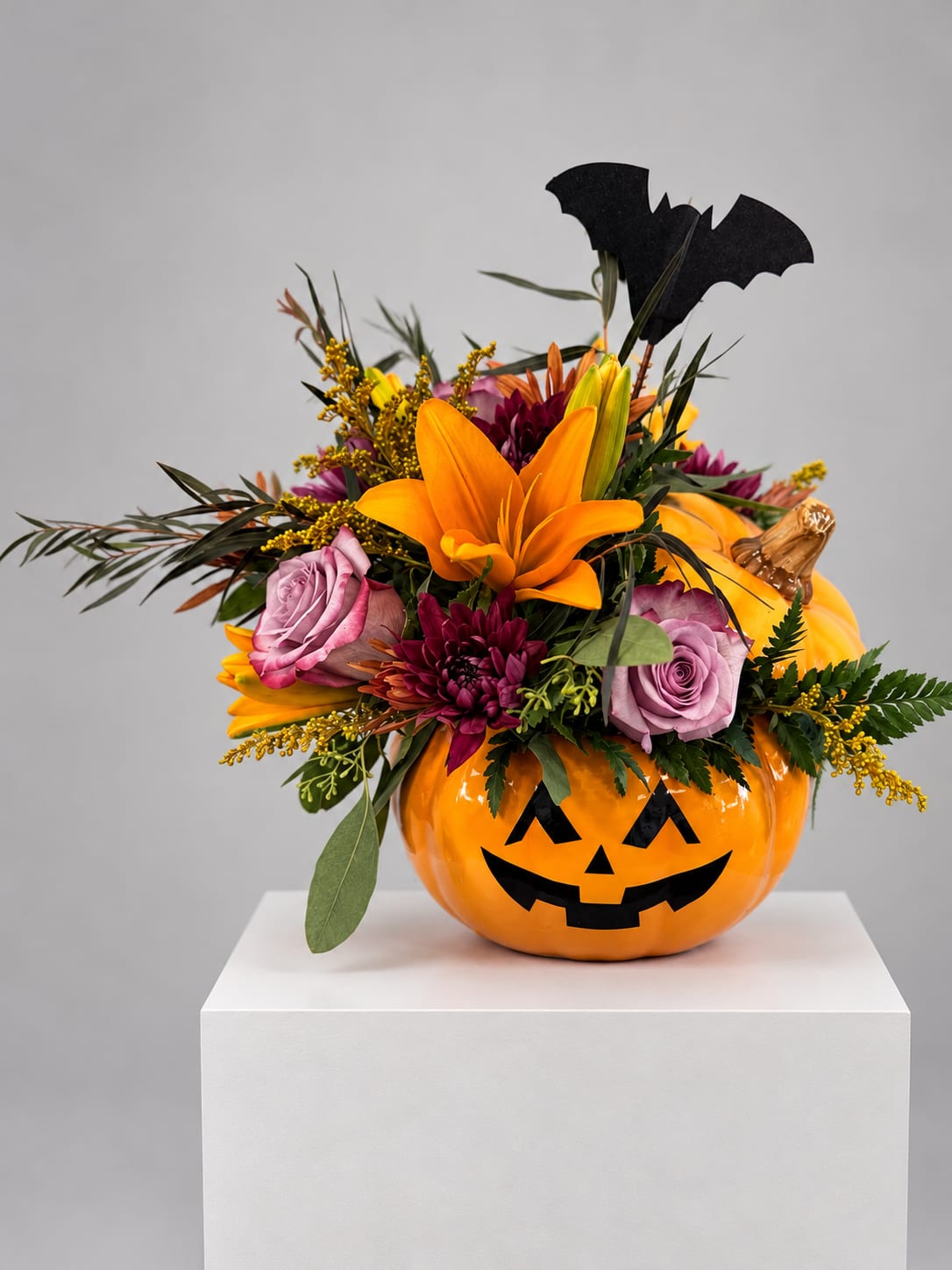 Halloween floral arrangement in a jack-o'-lantern container with roses and lilies