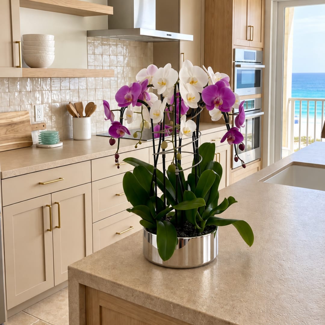 Purple and white orchids arranged in a silver pot on a kitchen counter