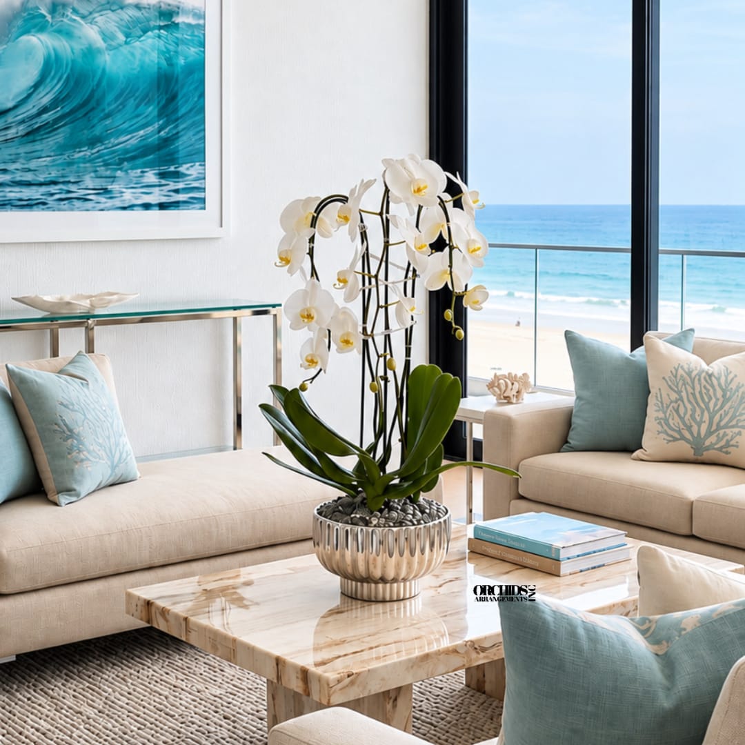White orchid arrangement in a metallic pot on a coffee table