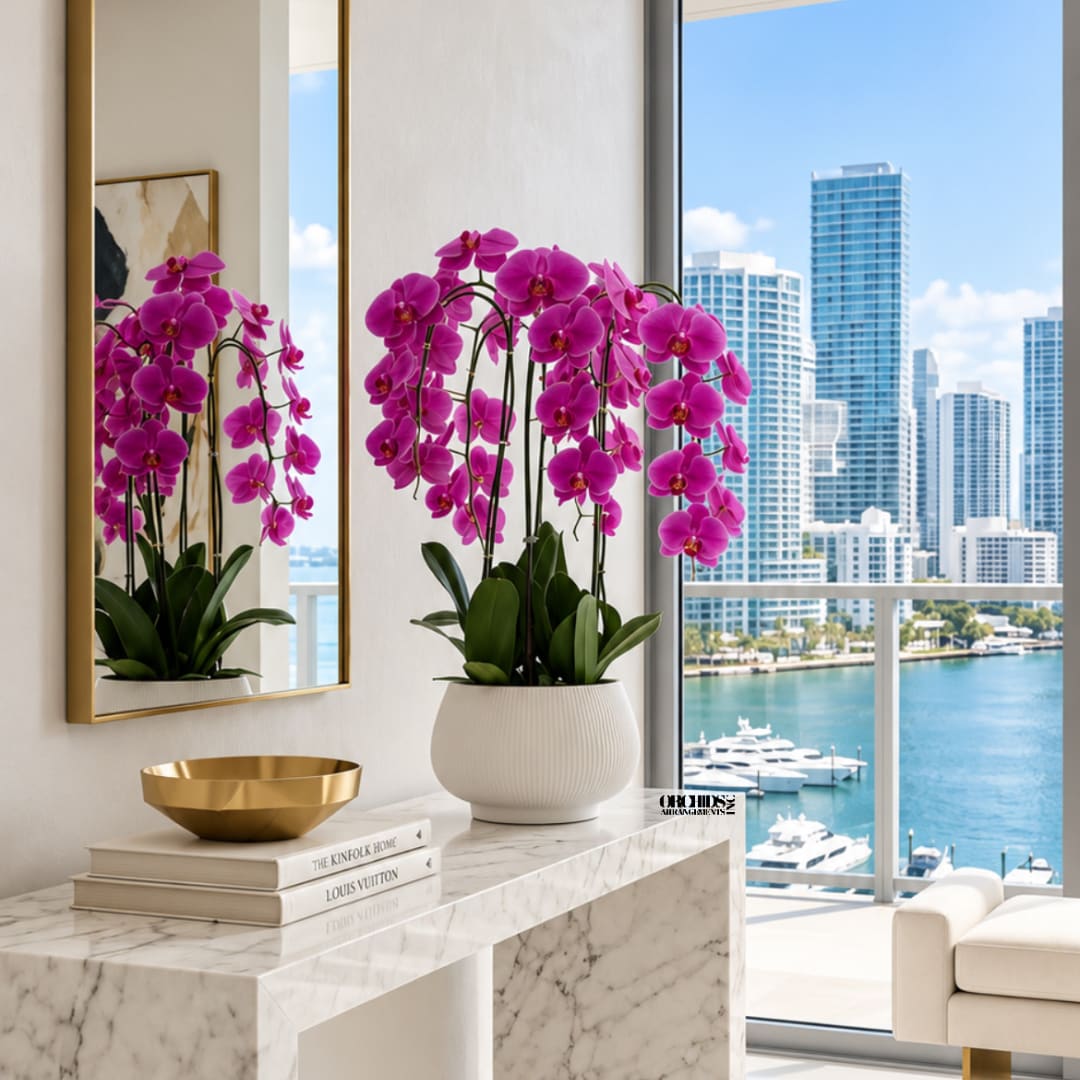 Pink orchid arrangement in a white pot on a marble console table