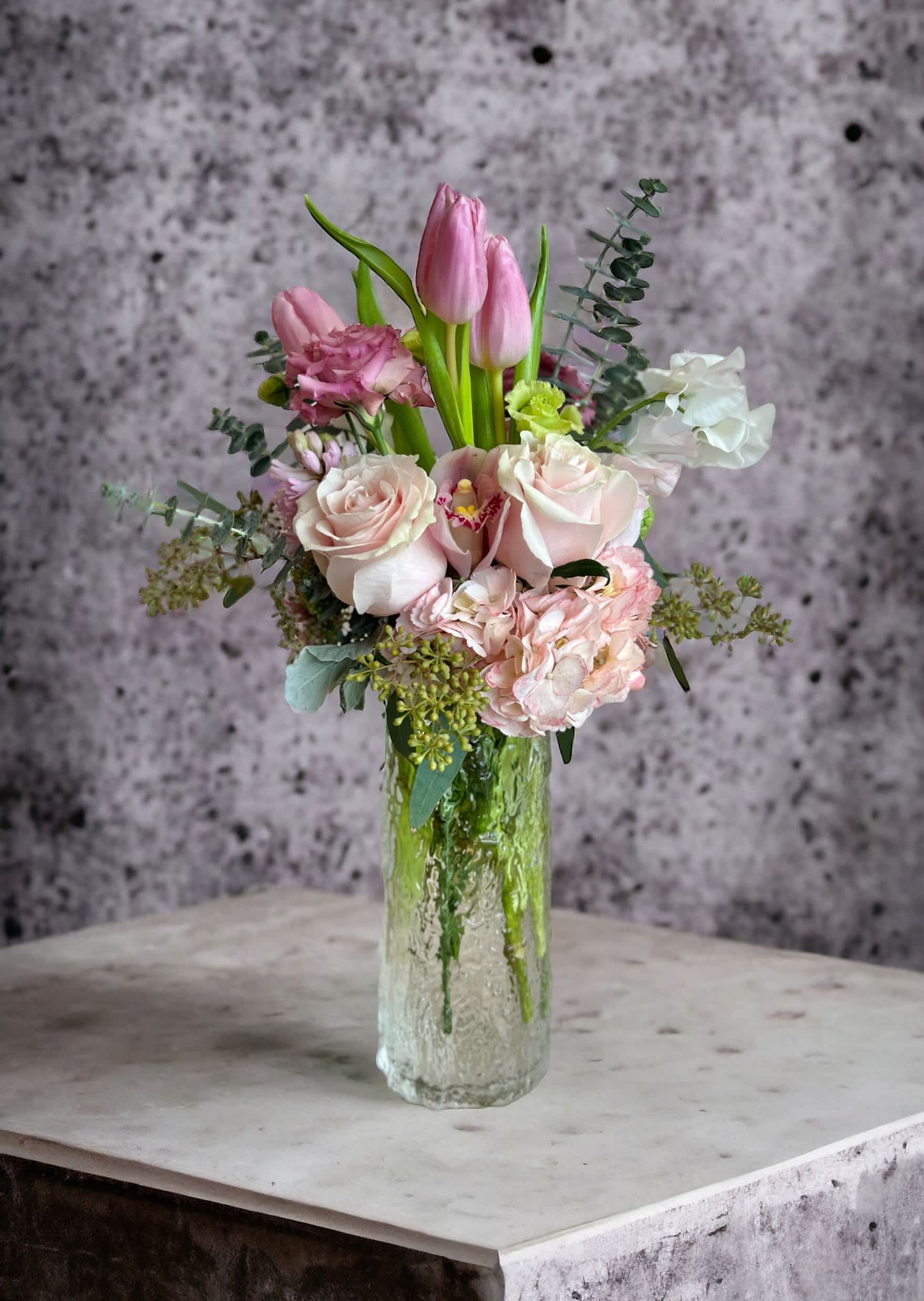 Pink tulips and pale roses arranged in a clear glass vase
