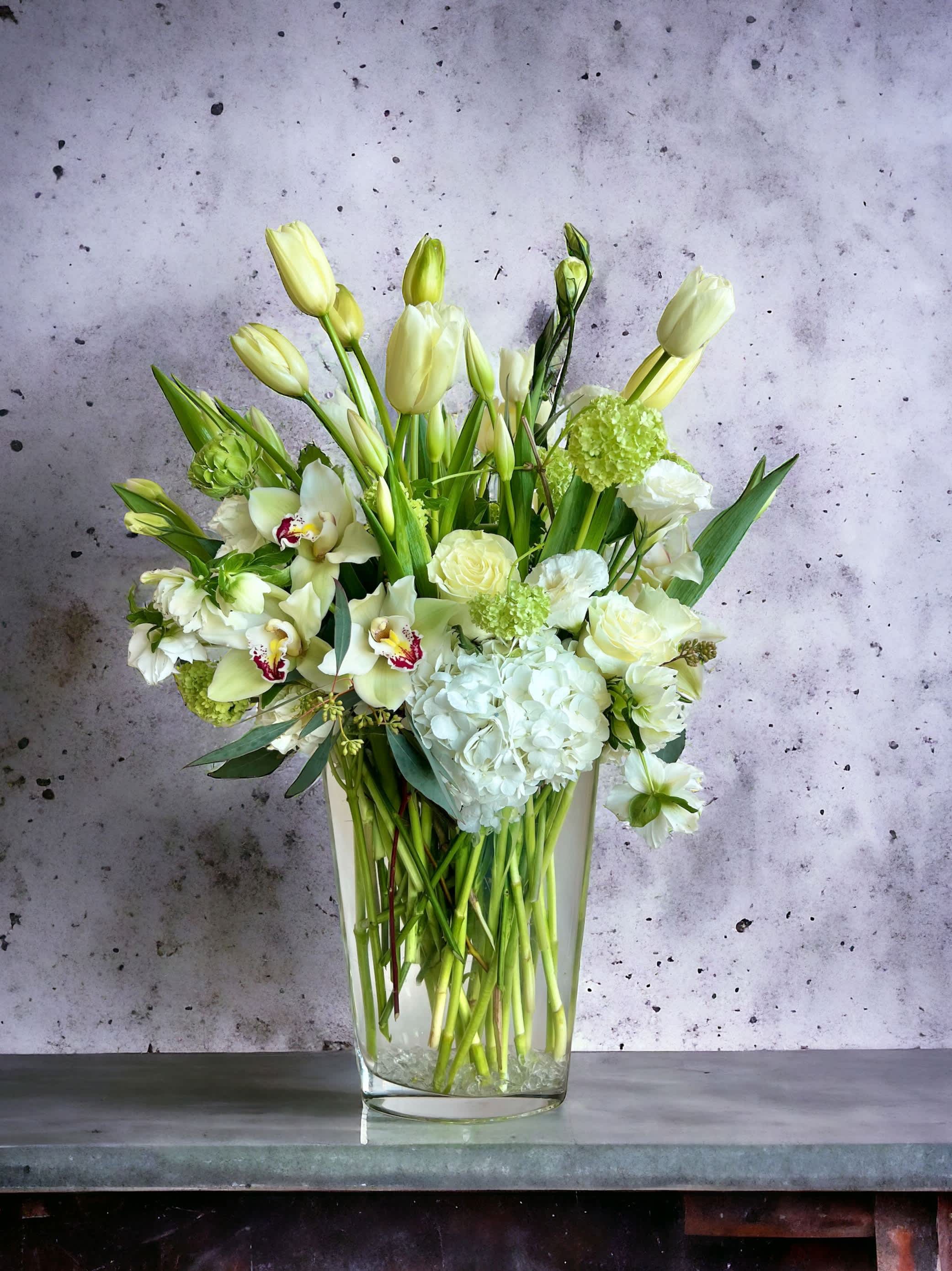 White and pale green floral arrangement in a clear glass vase