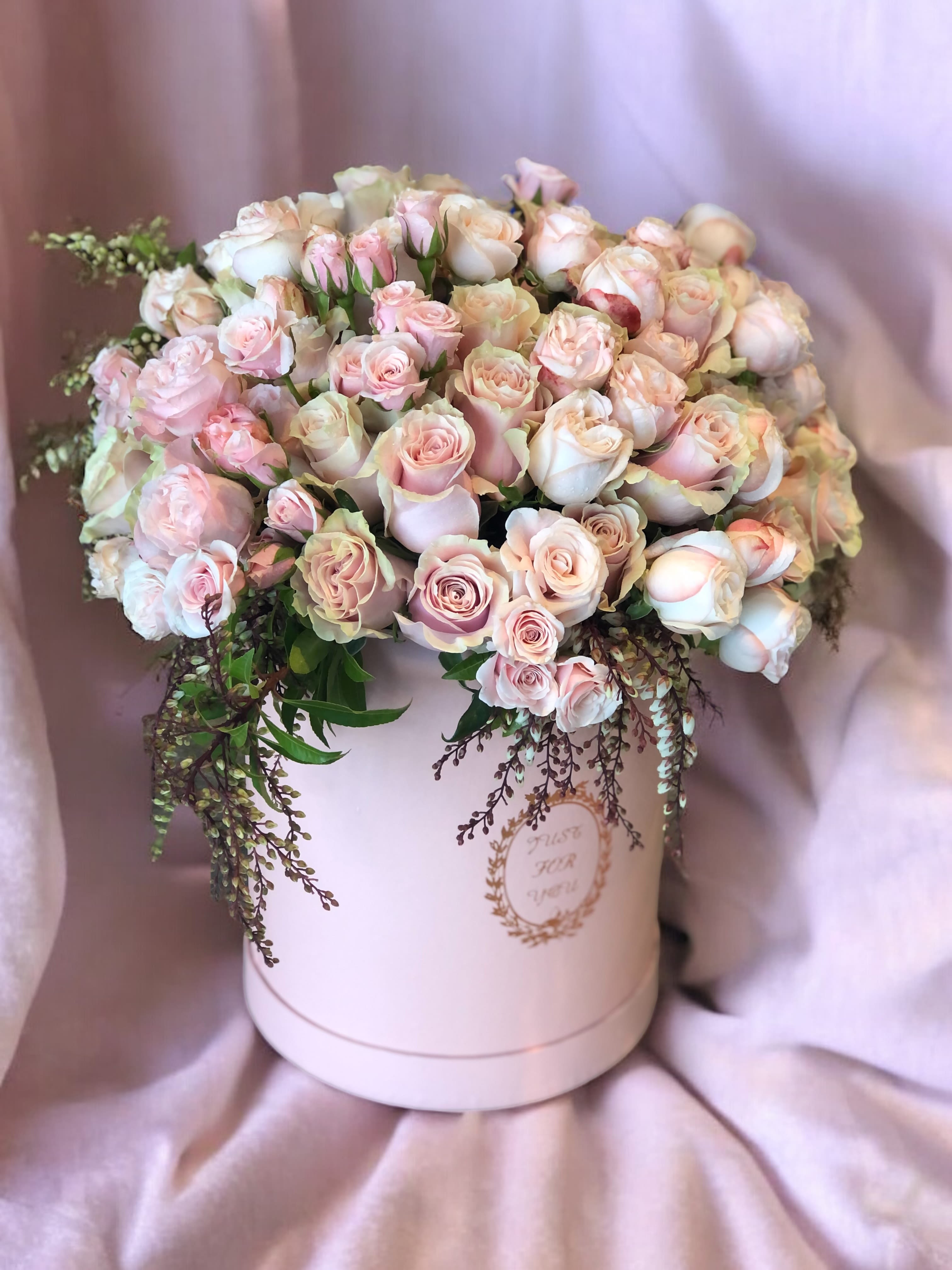 Pink and white roses arranged in a round hatbox