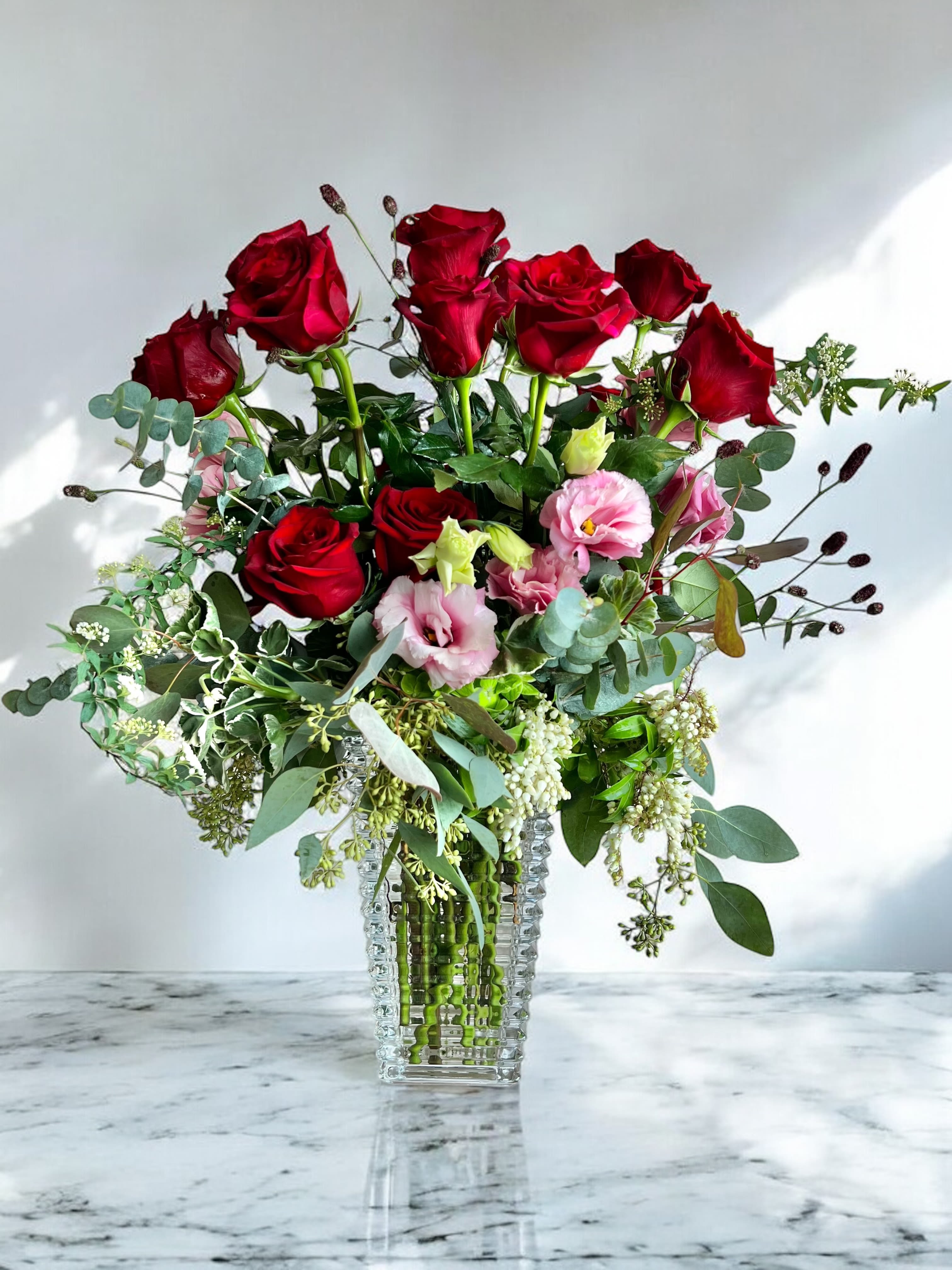 Red roses and pink lisianthus in a clear glass vase