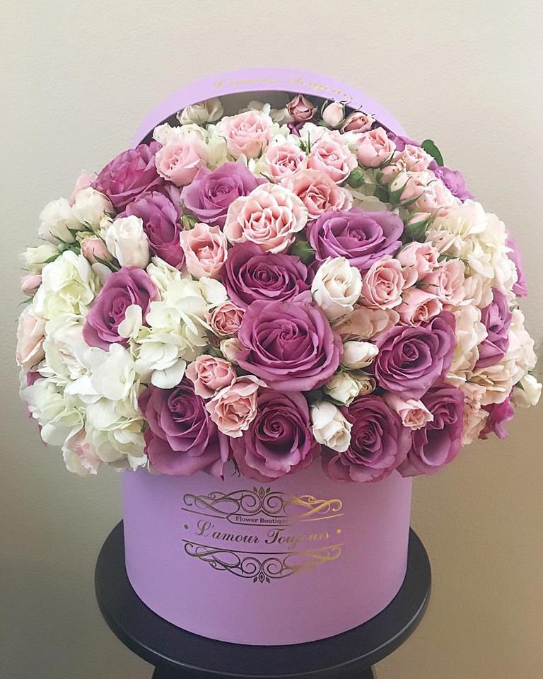 Pink and purple roses with white flowers in a lavender hat box