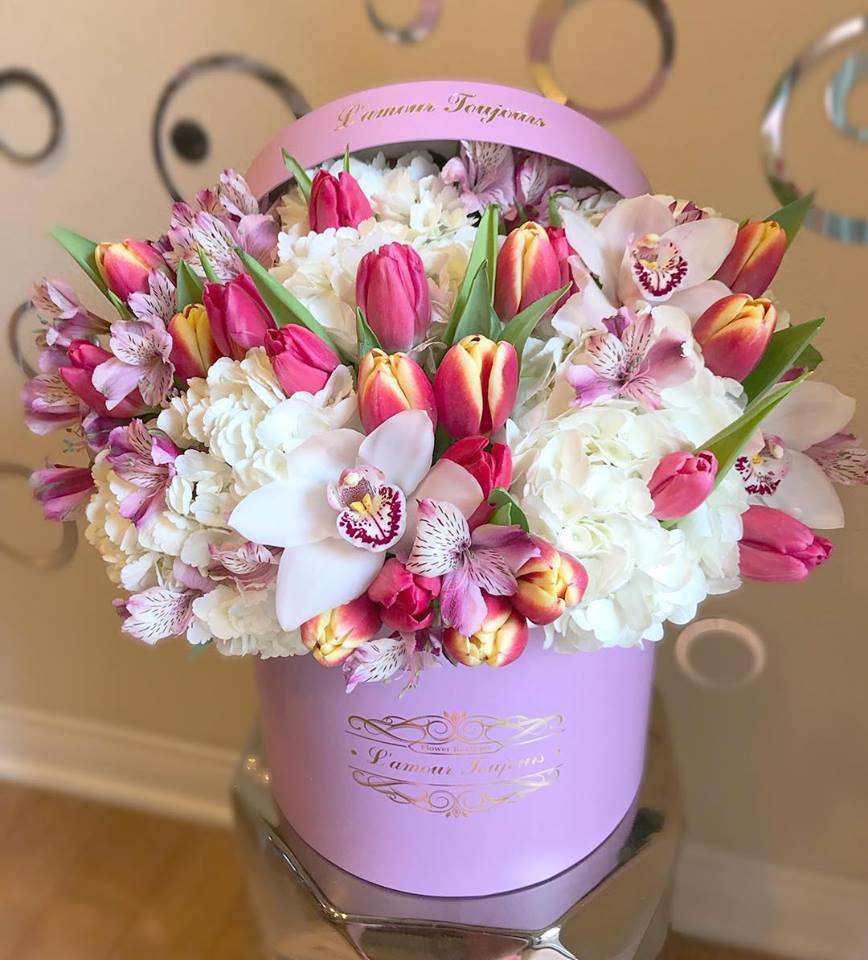 Round pink hat box of tulips, orchids, hydrangeas, and alstroemeria in white and pink tones