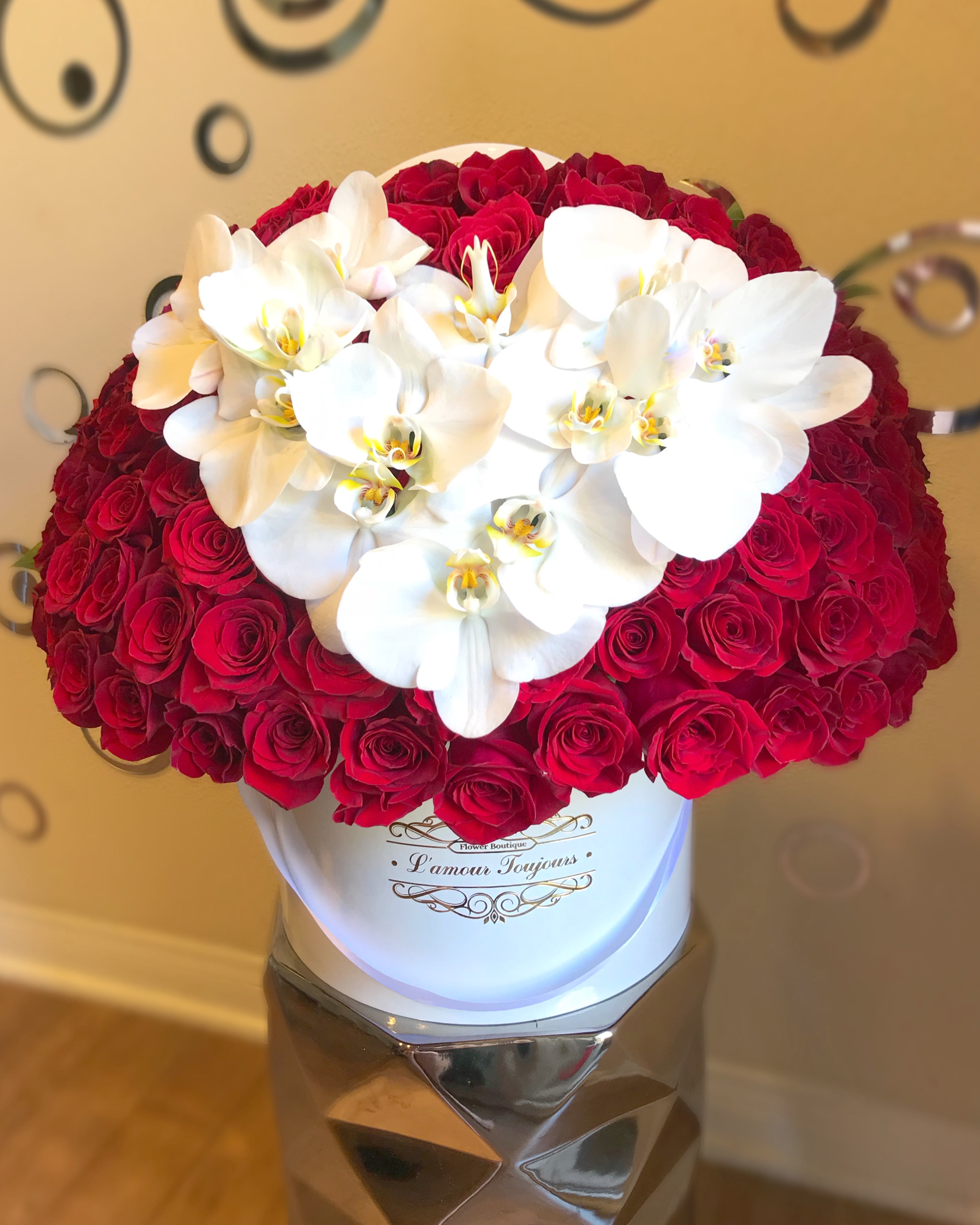 Red roses with white orchids in a white hat box