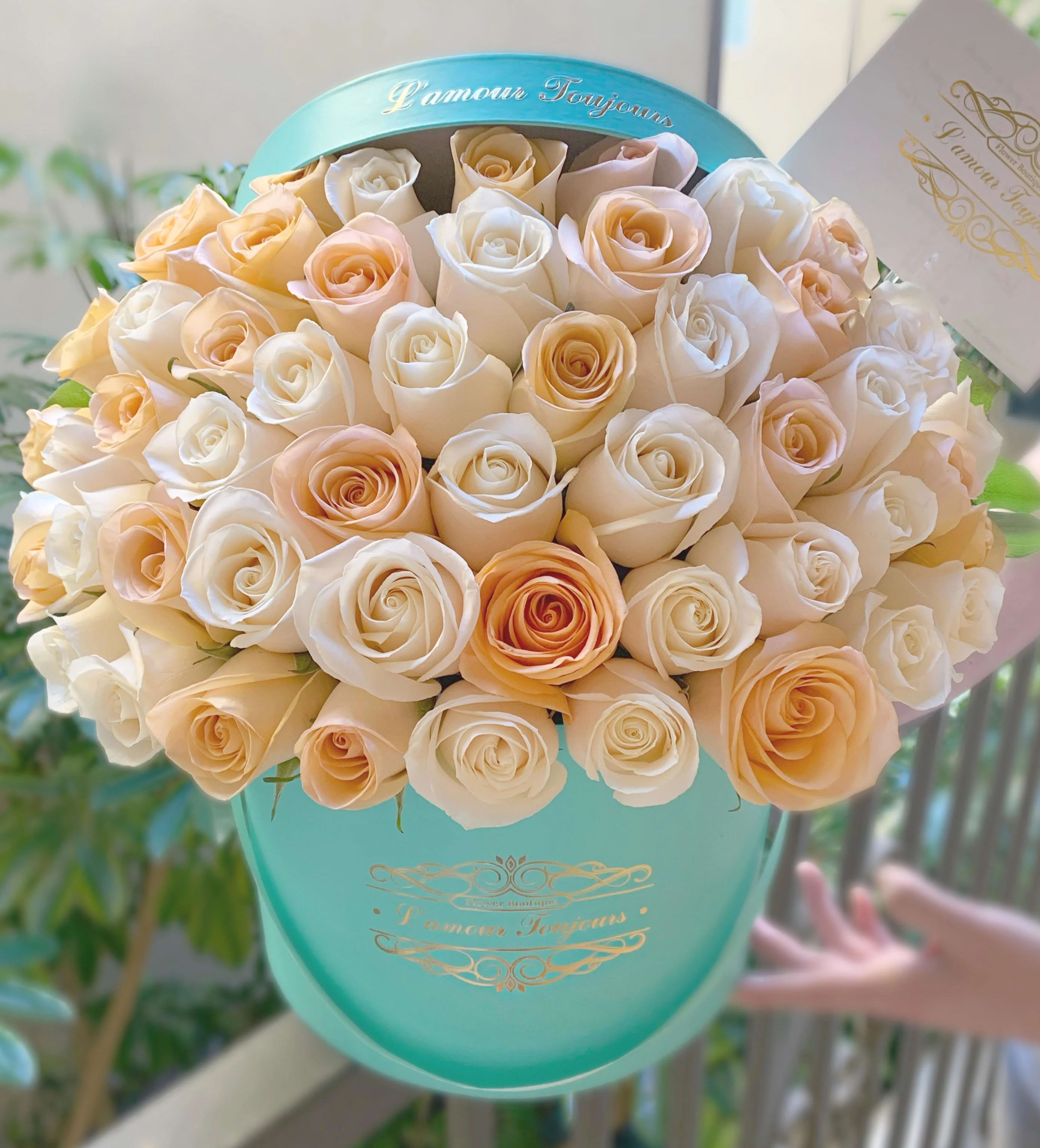 Bouquet of cream and peach roses in a turquoise hat box