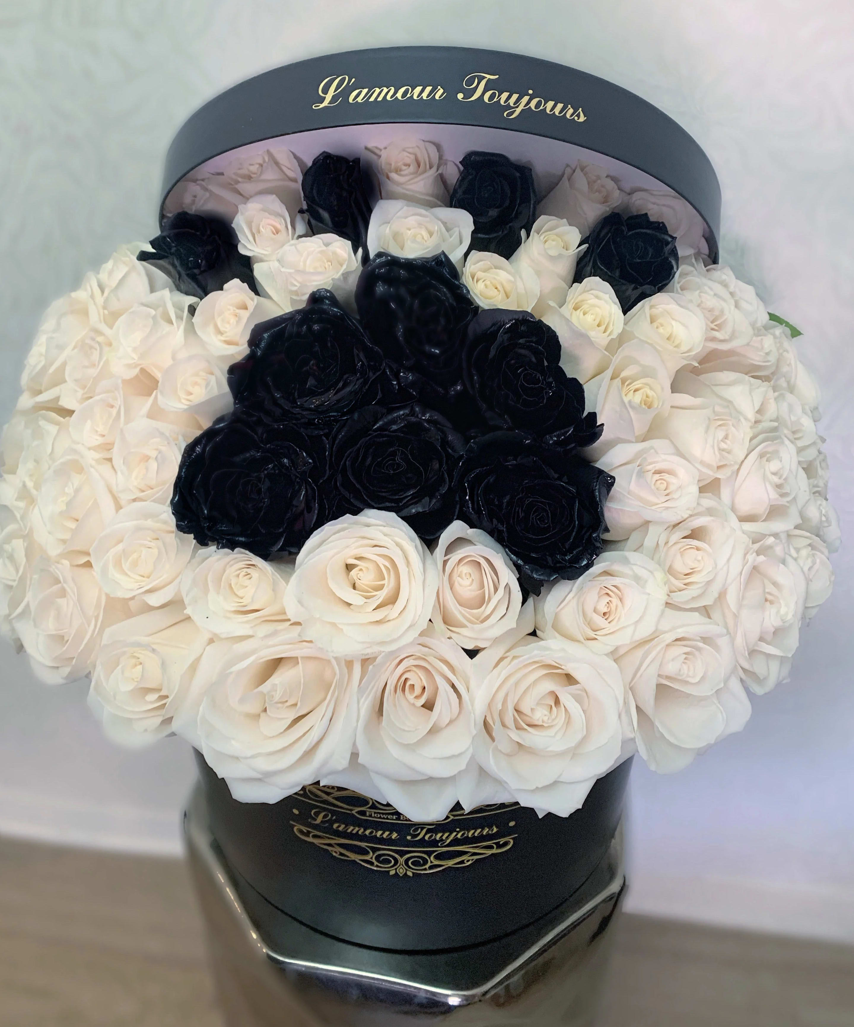 Black and white roses arranged in a round hat box