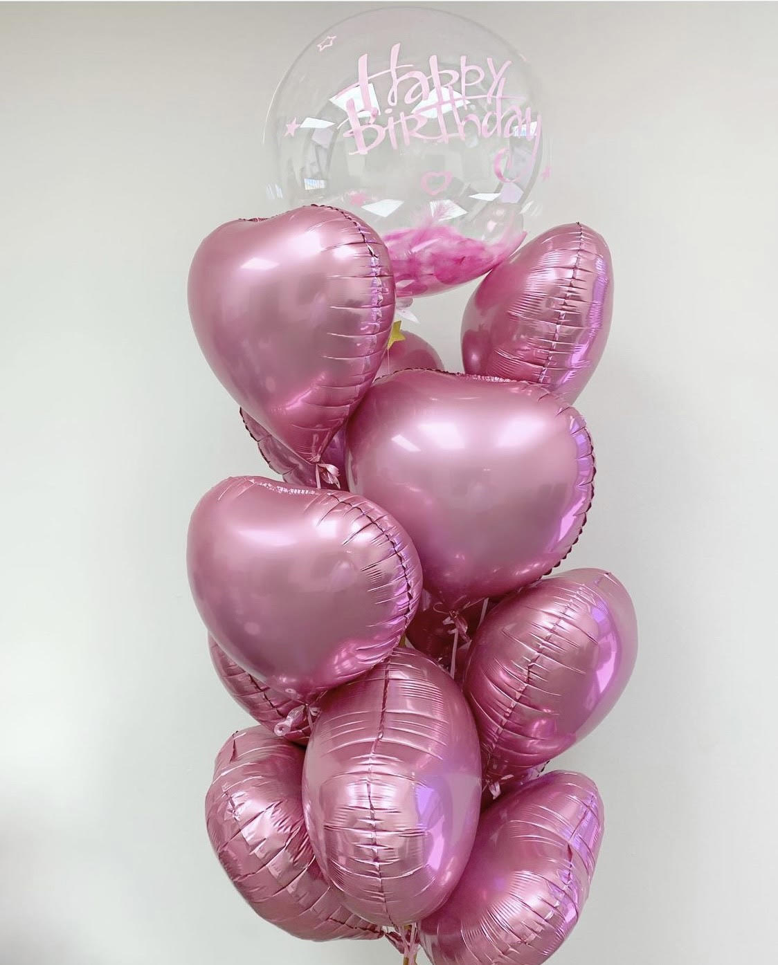 Cluster of pink heart balloons with a clear Happy Birthday balloon on top